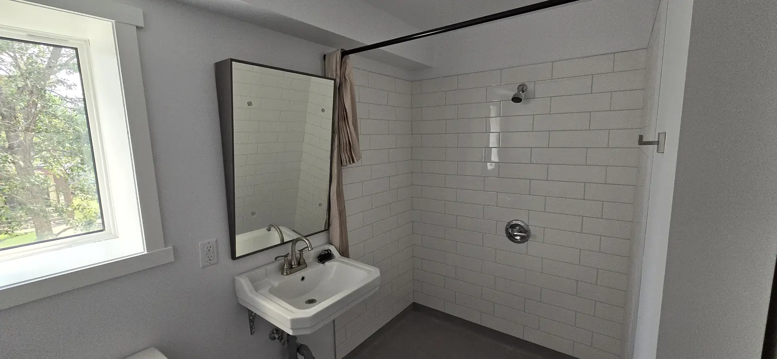 Tiled roll-in shower with wall-mounted sink