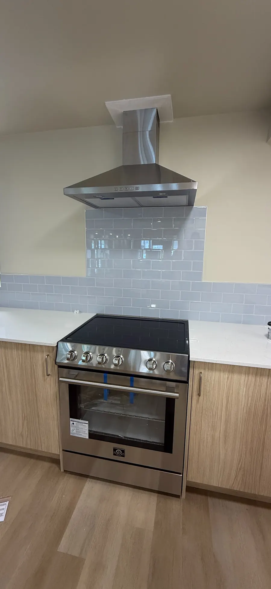 New suite kitchen with range, hood fan and tile backsplash
